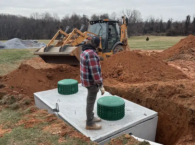 New concrete septic tank set in place with risers on a King and Sons installation