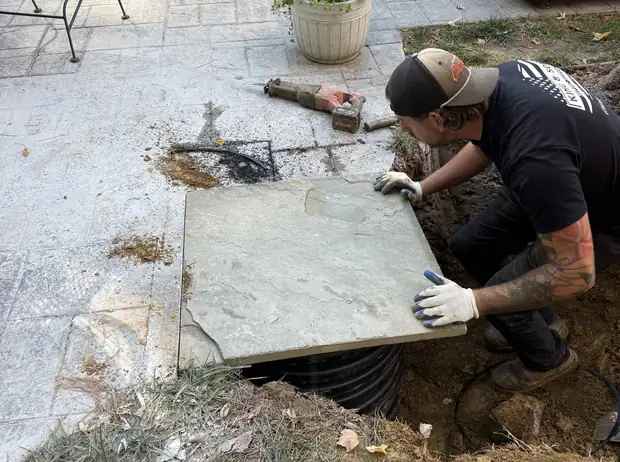 King and Sons technician lifting a concrete septic tank lid to inspect the system